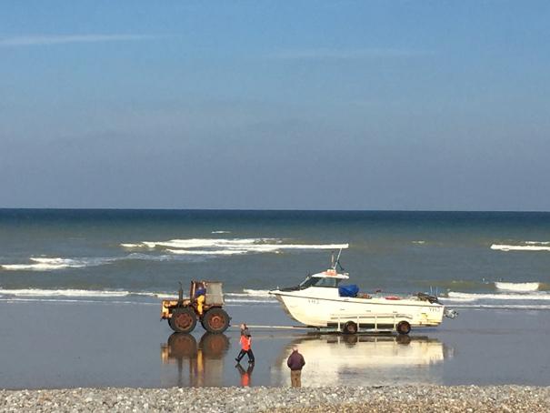 Tractor pulling a boat on the beach in North Norfolk